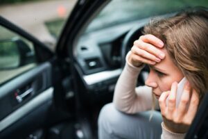 A distressed woman in a car, talking on a phone after automobile Accident Steps