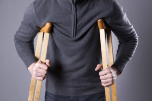 A person's torso and hands gripping wooden crutches, Massachusetts Personal Injury Case