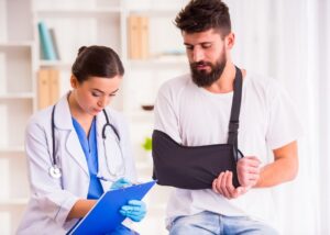 A doctor documenting an injured man with an arm sling.