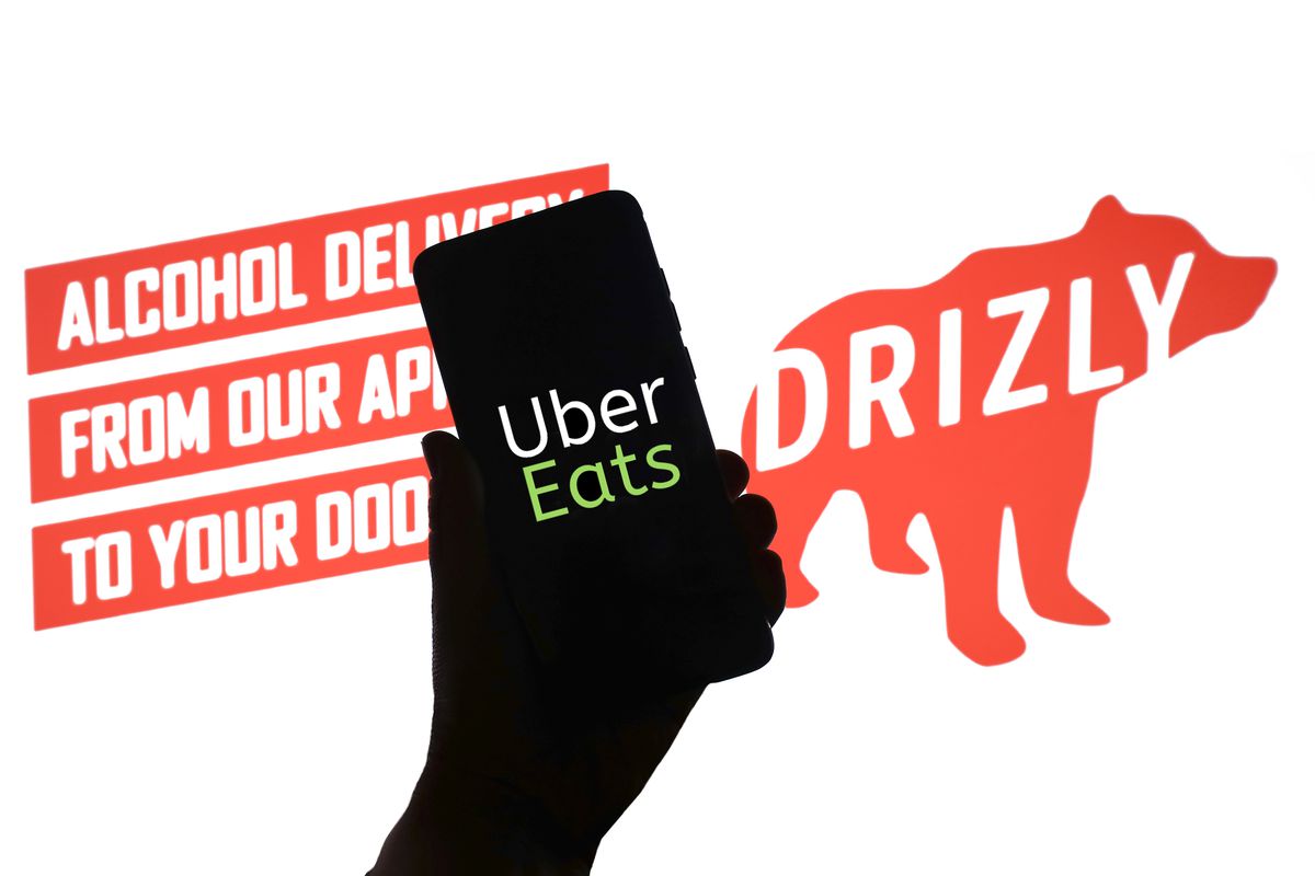 Uber Eats app on phone with alcohol delivery text and Drizly bear logo.